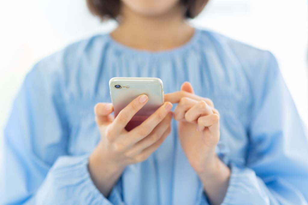 スマートフォンを操作している人物の手元を写したイメージ画像。ホームページ制作において、スマホ対応デザインやモバイル閲覧への最適化、ユーザー目線の使いやすさを表現している。